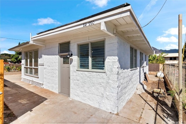 view of side of property featuring a patio area, concrete block siding, and fence