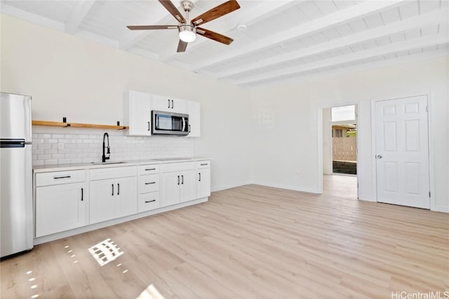 kitchen featuring beam ceiling, open shelves, a sink, appliances with stainless steel finishes, and tasteful backsplash