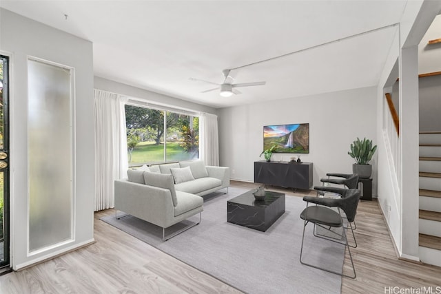 living room with light hardwood / wood-style flooring and ceiling fan