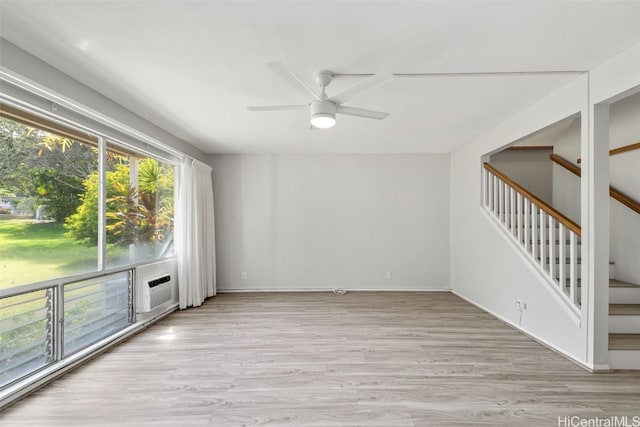 empty room featuring ceiling fan, a wall mounted air conditioner, and light hardwood / wood-style floors