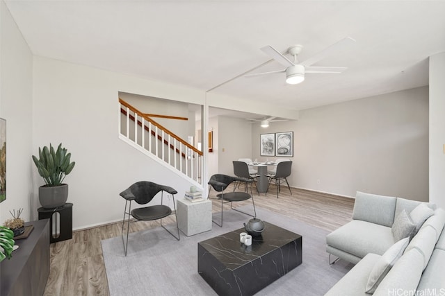 living area featuring ceiling fan, stairs, and wood finished floors