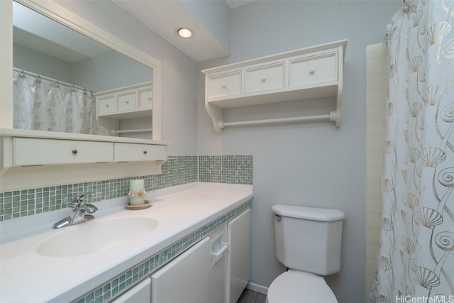 bathroom featuring vanity, toilet, and tasteful backsplash