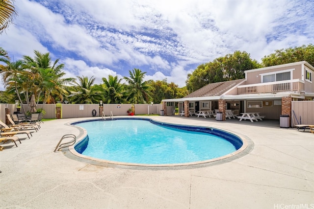 community pool with a patio and fence