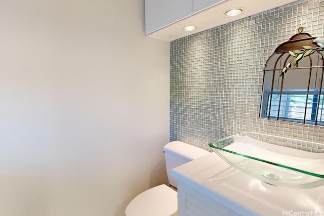 bathroom featuring toilet, vanity, and tile walls