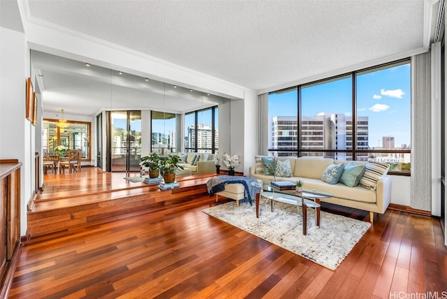 living room featuring wood-type flooring, a textured ceiling, a wall of windows, and ornamental molding