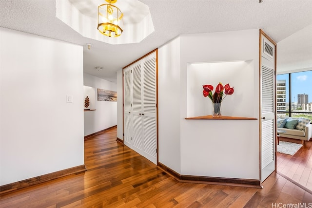 hallway with a textured ceiling, a notable chandelier, and dark wood-type flooring