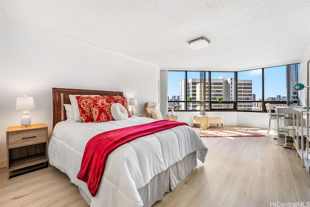 bedroom with expansive windows, a textured ceiling, and light hardwood / wood-style flooring