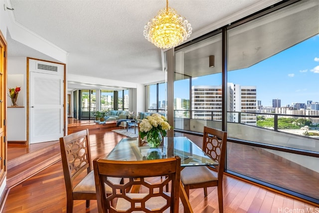 dining space with hardwood / wood-style floors, floor to ceiling windows, an inviting chandelier, ornamental molding, and a textured ceiling