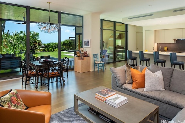 living room featuring wood-type flooring, an inviting chandelier, floor to ceiling windows, and sink