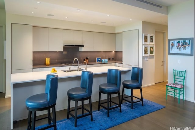 kitchen featuring backsplash, light hardwood / wood-style flooring, a breakfast bar area, and sink