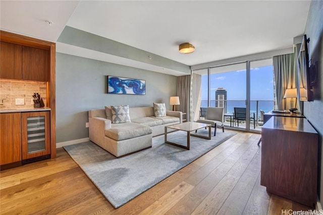 living room featuring a water view, wine cooler, expansive windows, and light hardwood / wood-style floors