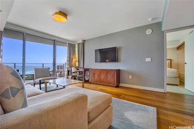 living room with hardwood / wood-style flooring, a water view, and a wall of windows