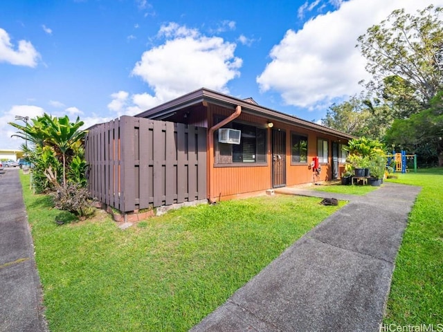 view of front of property featuring an AC wall unit and a front yard