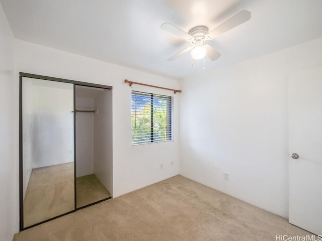 unfurnished bedroom with ceiling fan, light colored carpet, and a closet