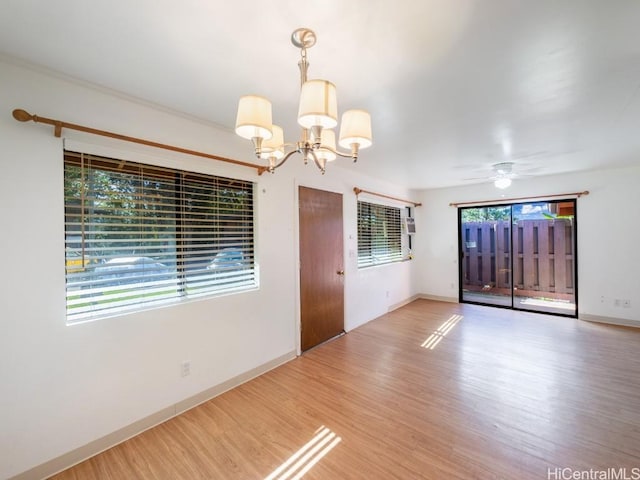 spare room with wood-type flooring and ceiling fan with notable chandelier