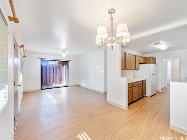 kitchen featuring plenty of natural light, ceiling fan with notable chandelier, light hardwood / wood-style flooring, decorative light fixtures, and white fridge