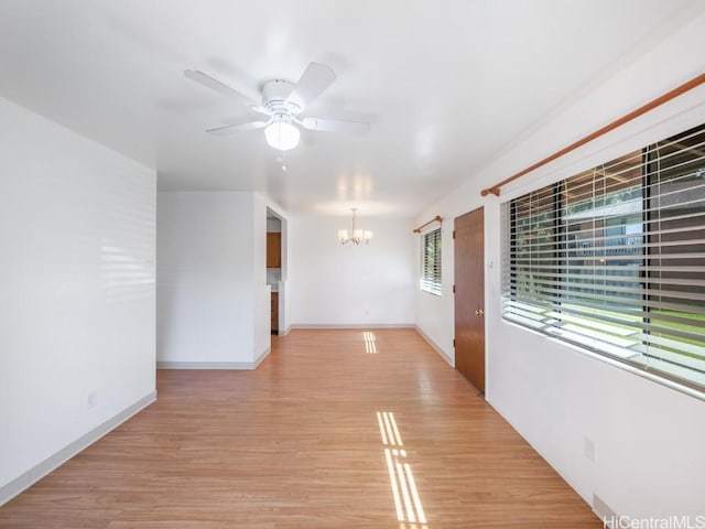 unfurnished room featuring ceiling fan with notable chandelier and light hardwood / wood-style flooring