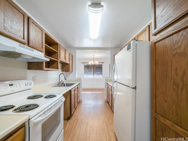 kitchen with sink, a notable chandelier, light hardwood / wood-style floors, pendant lighting, and white appliances