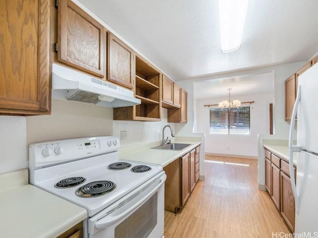 kitchen featuring light wood-type flooring, white appliances, sink, decorative light fixtures, and a notable chandelier