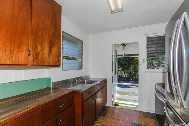 kitchen featuring dark parquet flooring, sink, appliances with stainless steel finishes, and tasteful backsplash