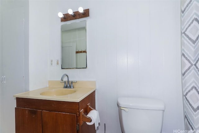 bathroom featuring vanity, toilet, and wood walls