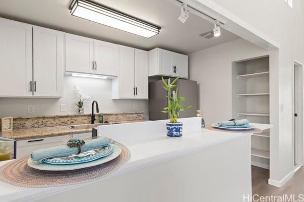 kitchen with stainless steel refrigerator, white cabinetry, sink, hardwood / wood-style floors, and track lighting