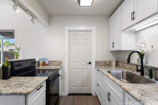 kitchen with light stone countertops, white cabinetry, sink, and black / electric stove