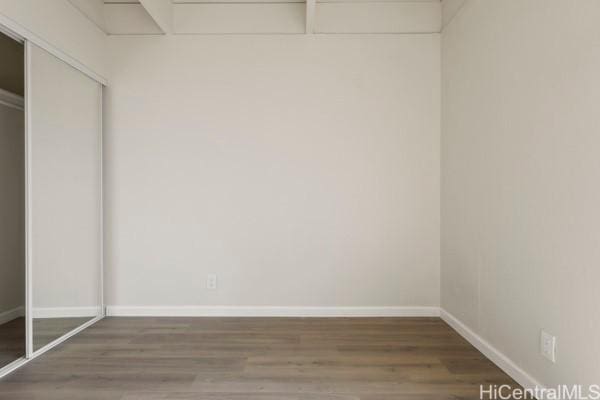 unfurnished bedroom with dark hardwood / wood-style floors and a closet