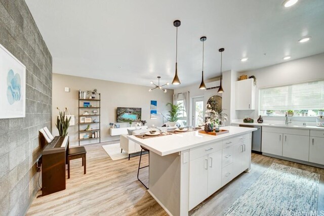 kitchen with sink, a center island, pendant lighting, light hardwood / wood-style floors, and white cabinets