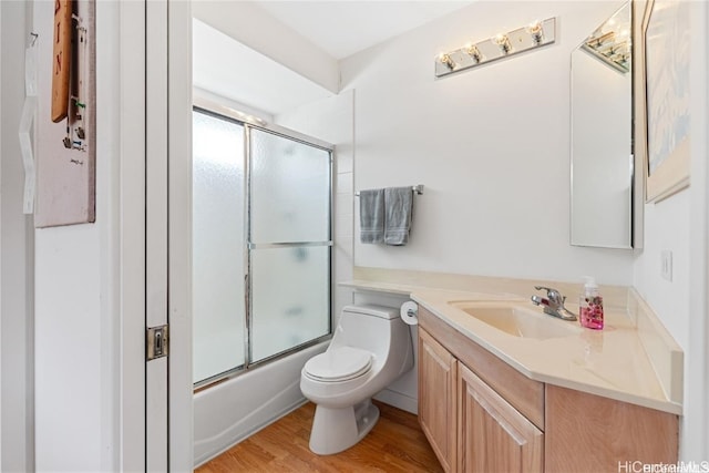 full bathroom featuring toilet, combined bath / shower with glass door, wood-type flooring, and vanity