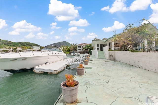 view of patio with a dock and a water and mountain view