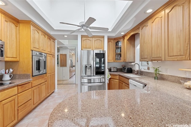 kitchen featuring sink, light stone countertops, light tile patterned floors, a tray ceiling, and stainless steel appliances