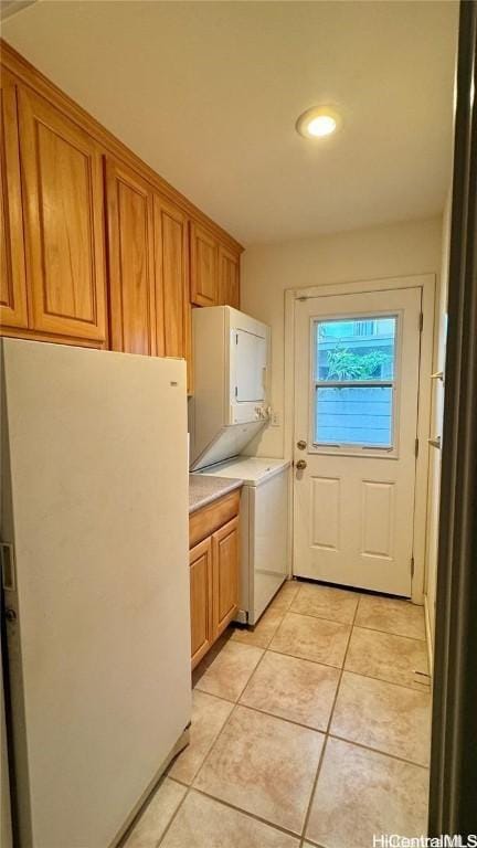 washroom featuring light tile patterned flooring, cabinets, and stacked washer and clothes dryer