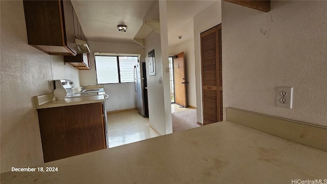 kitchen featuring stainless steel refrigerator, dark brown cabinetry, and a textured ceiling