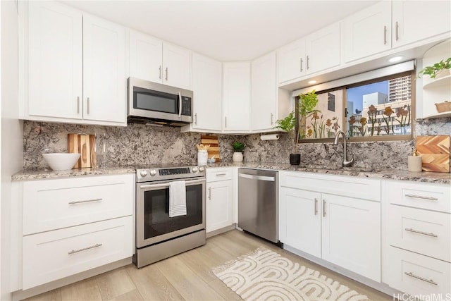 kitchen with white cabinetry, stainless steel appliances, sink, and decorative backsplash