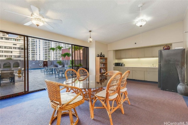 carpeted dining area with ceiling fan, vaulted ceiling, sink, and a textured ceiling