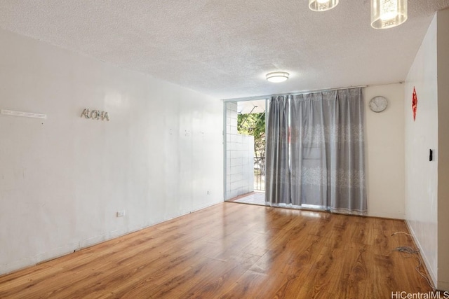 unfurnished room with a textured ceiling and hardwood / wood-style flooring