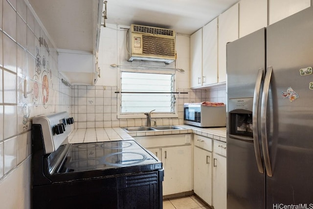 kitchen featuring white cabinetry, sink, tile counters, a wall unit AC, and appliances with stainless steel finishes