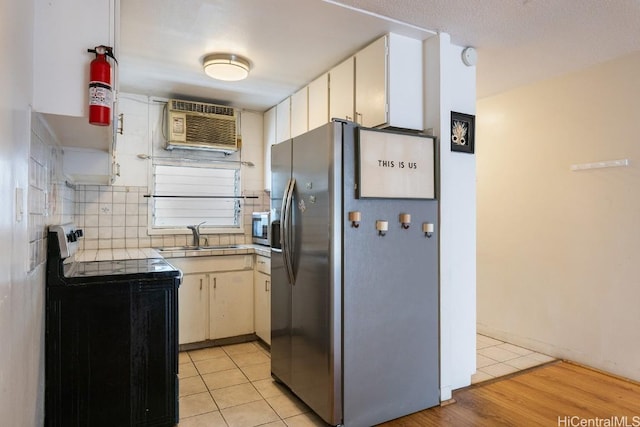 kitchen with sink, light tile patterned floors, tasteful backsplash, white cabinets, and appliances with stainless steel finishes