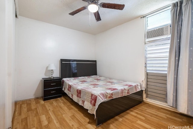 bedroom featuring ceiling fan, light wood-type flooring, and a textured ceiling