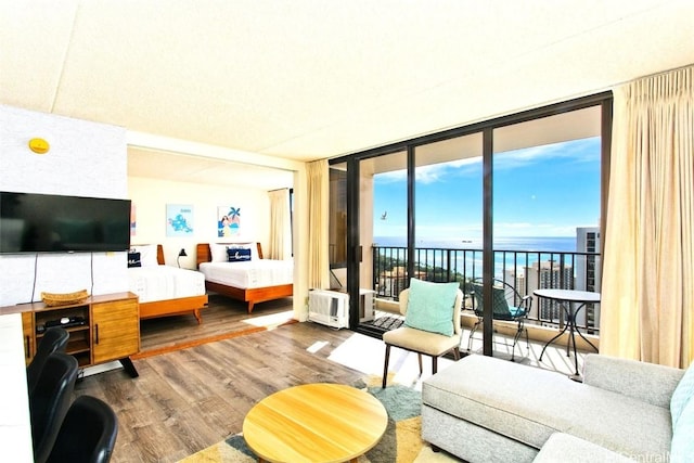 bedroom with a water view, access to outside, hardwood / wood-style floors, and a wall of windows