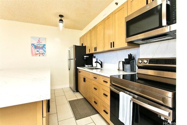 kitchen with sink, stainless steel appliances, tasteful backsplash, a textured ceiling, and light tile patterned flooring