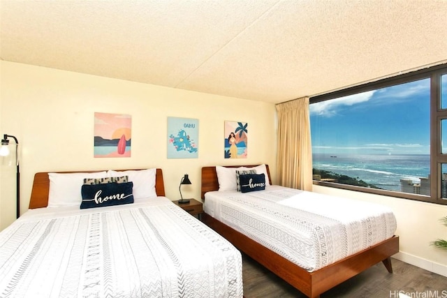 bedroom featuring a water view, dark wood-type flooring, and a textured ceiling