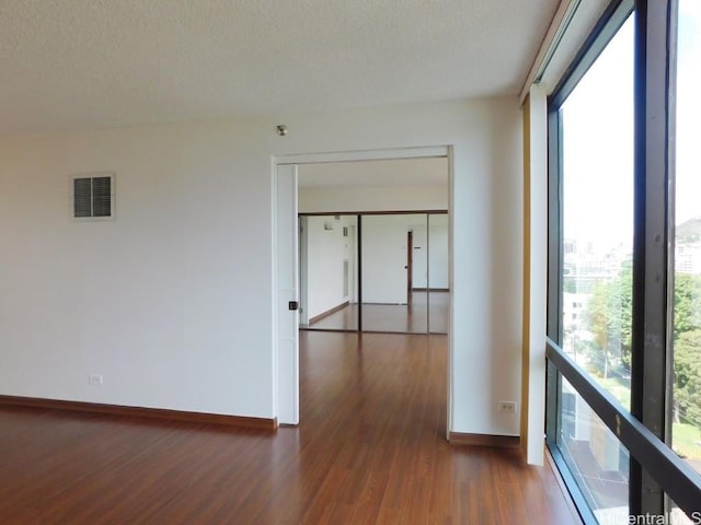 unfurnished room with a textured ceiling and dark hardwood / wood-style flooring