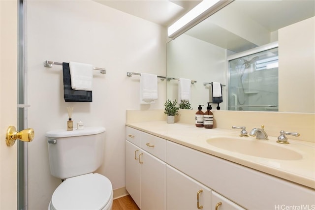 bathroom with hardwood / wood-style floors, vanity, toilet, and a shower with door