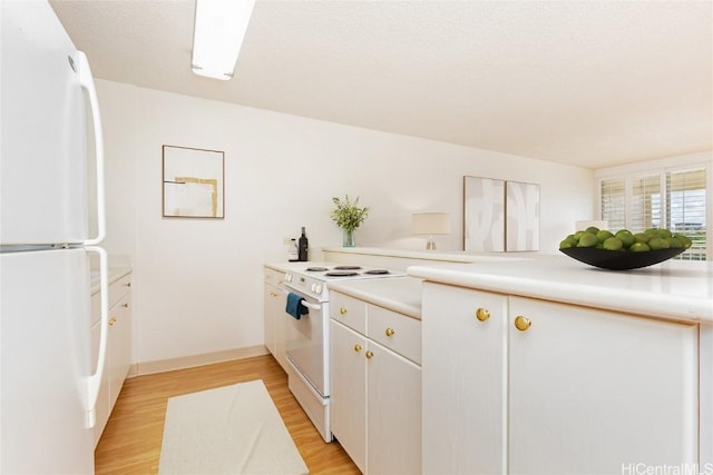 kitchen with white cabinets, light wood-type flooring, and white appliances