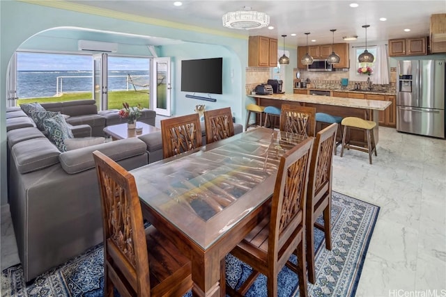 dining room featuring a wall mounted air conditioner, crown molding, sink, and a water view