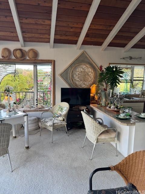 carpeted living room featuring vaulted ceiling with beams and wood ceiling