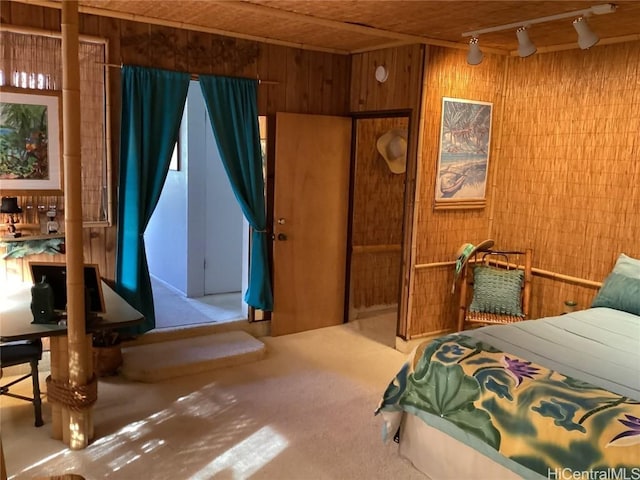 carpeted bedroom featuring wood walls and rail lighting