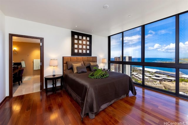 bedroom with hardwood / wood-style floors, floor to ceiling windows, a water view, and multiple windows